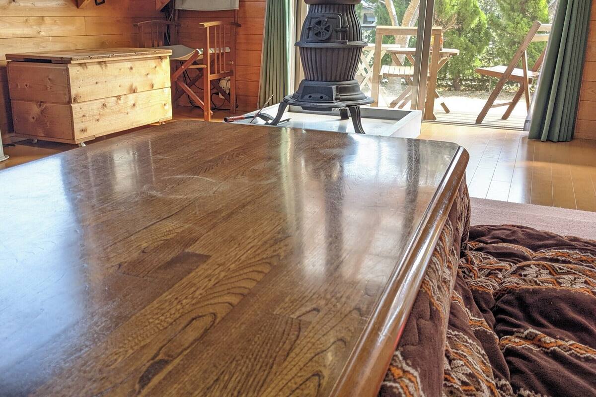 Una mesa de comedor de madera en una habitación con un cofre de madera, un calentador y vistas al exterior.