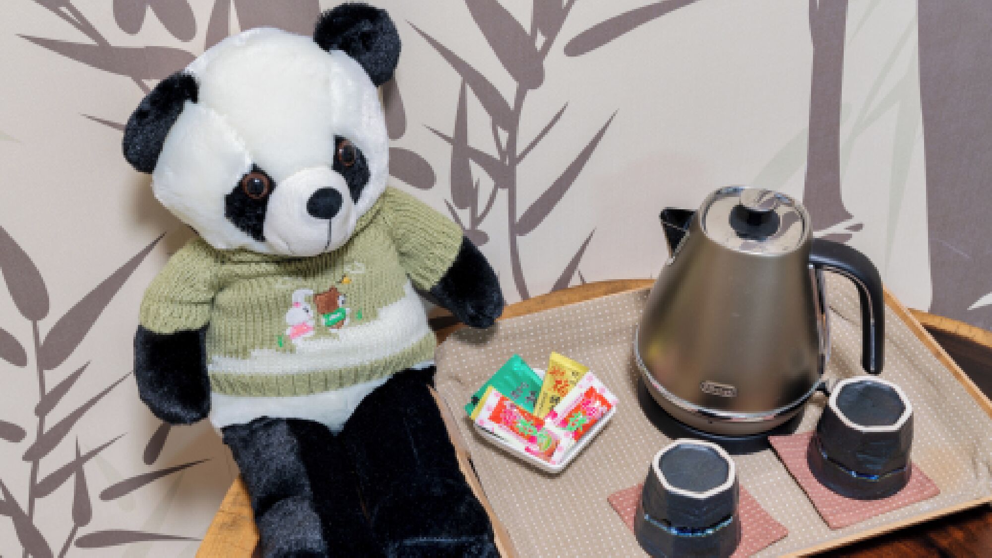 A plush panda toy, a teapot, and two cups on a tray.