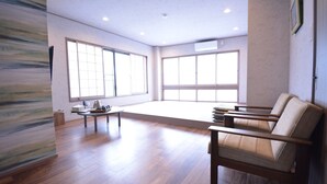 A spacious room with wooden flooring, a sofa, a small table, and large windows. - Shirahama no Yado Daigo (Shirahama)