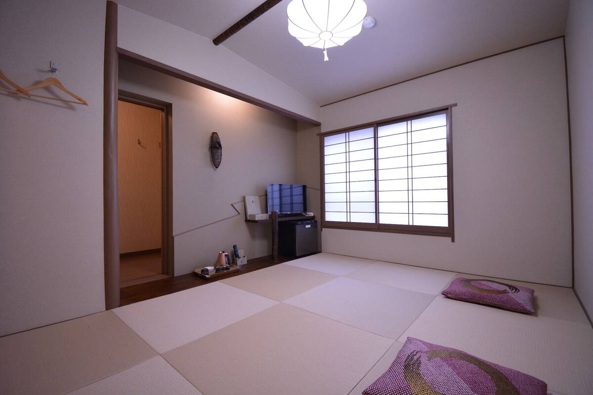 Een traditionele Japanse kamer met tatami vloeren, een schuifdeur, een televisie en een raam met shoji schermen.