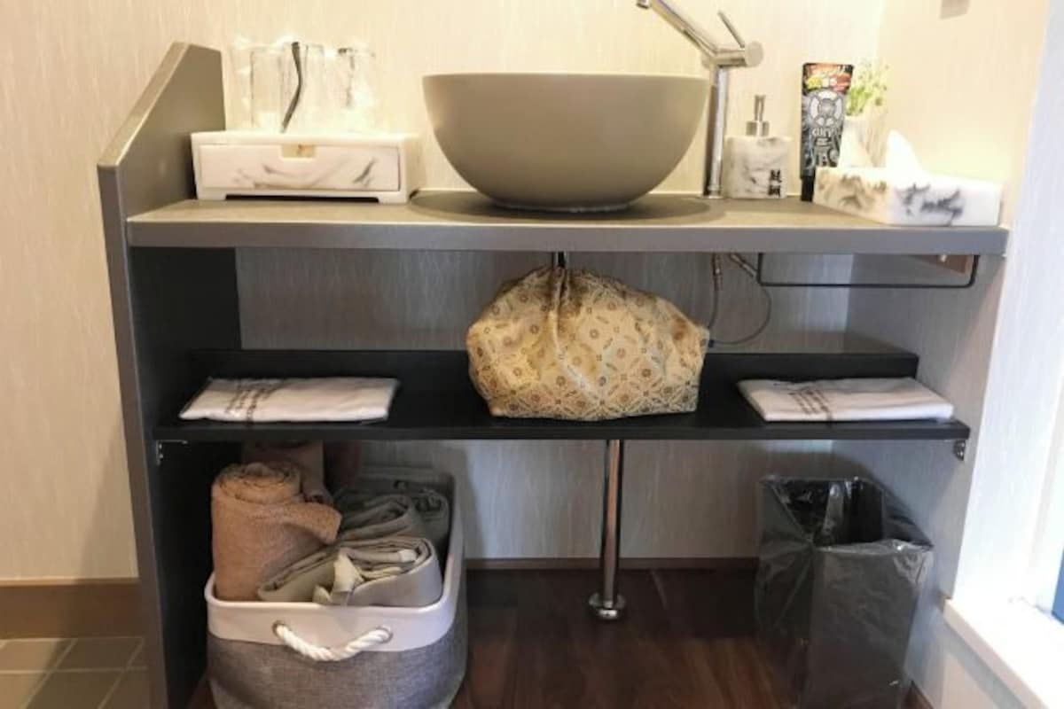 Un coin cuisine avec un saladier, une poubelle et un sac posé sur une étagère.