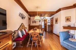 A dining area with a wooden table, chairs, and a television on the left. - Casa Amalia, with panoramic terrace (Cortina d´Ampezzo)