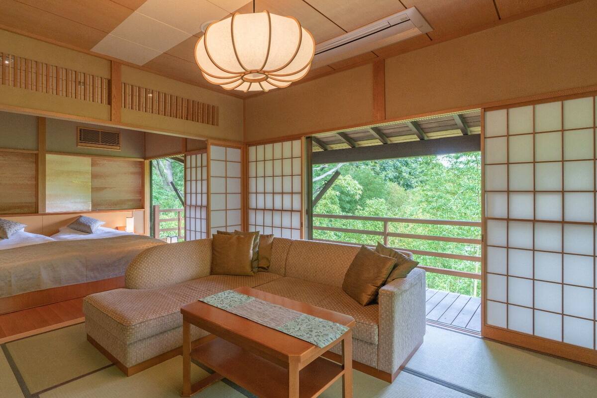 Ein traditioneller japanischer Raum mit Tatami-Boden, niedrigem Bett, Sofa und Tisch.