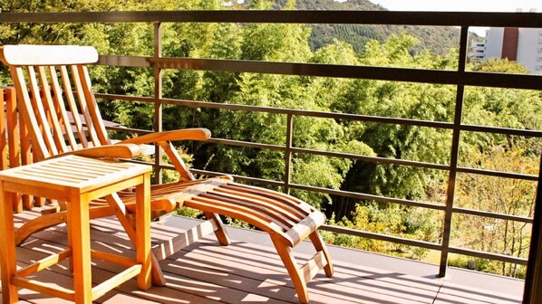 Un balcon doté de mobilier en bois et offrant une vue sur une zone boisée.