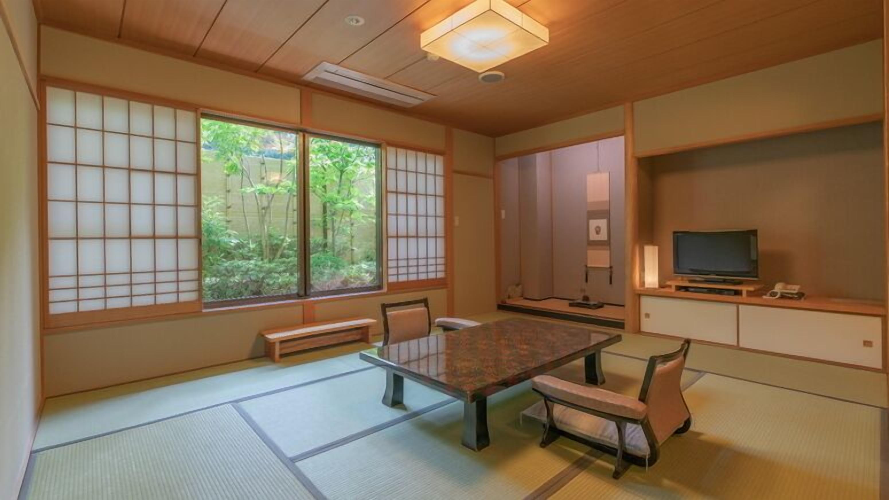 A traditional Japanese room with tatami flooring, a low table, and a television on a wooden stand.
