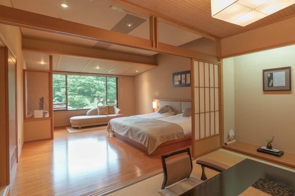 Ein geräumiges Schlafzimmer mit einem großen Bett, einem Schreibtisch und Blick auf Grünflächen.