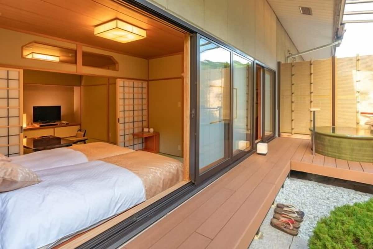 Ein Hotelzimmer mit einem großen Bett, einem Fernseher, einem kleinen Schreibtisch und einer Whirlwanne.