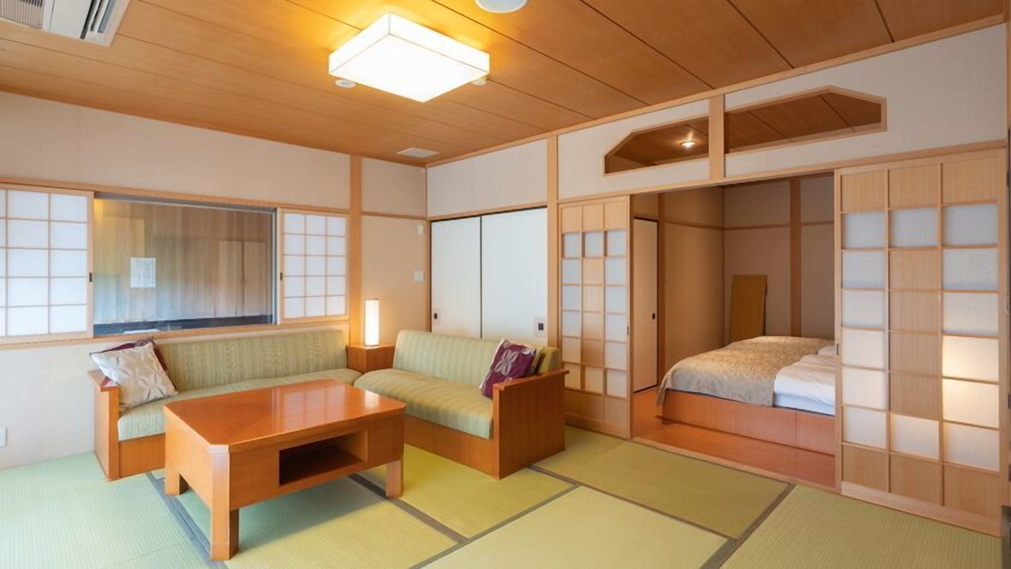 A traditional Japanese room with tatami flooring, a low wooden table, a sofa, and sliding shoji doors.