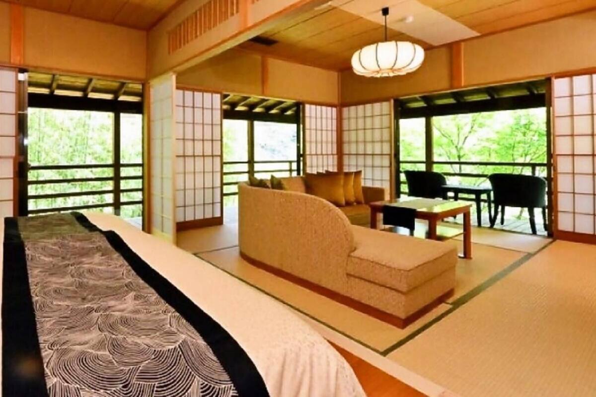 Ein traditioneller japanischer Raum mit Tatami-Böden, einem niedrigen Tisch, einer Couch und Schiebetüren.