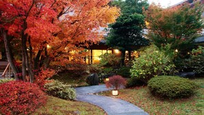 A garden with a stone pathway leading to a building with traditional architecture. - Narashinonosato Gyokusui (Higashiizu)