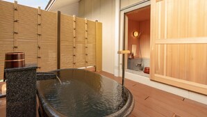 A hot spring bath area with a wooden fence, a stone basin, and a wooden door leading to a bathroom. - Narashinonosato Gyokusui (Higashiizu)