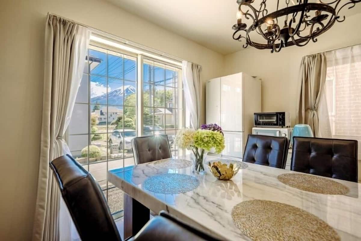 Un espace repas comprenant une table, des chaises, un lustre et une vue sur l’extérieur.