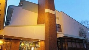 Ein modernes Gebäude mit einem markanten Backsteinturm und einem Glas Eingang.
