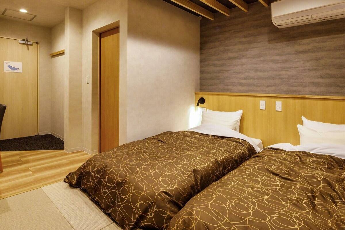 A hotel room with two beds, a desk, and a chair.