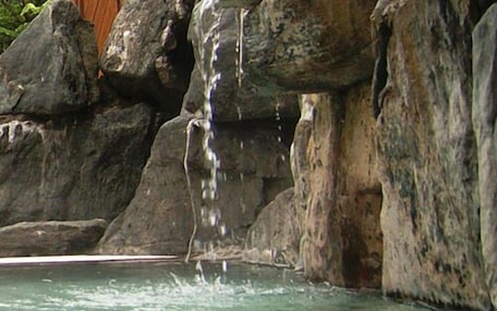 A natural rock formation with a clear water body in front.