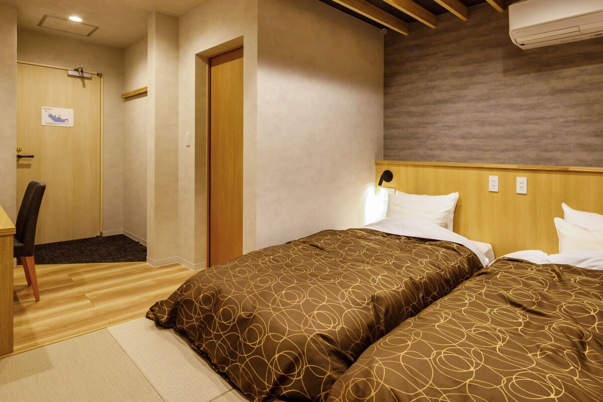 Ett hotellrum med två sängar, ett skrivbord och en stol.