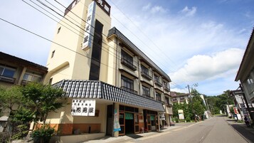 Un edificio de varios pisos con techo de tejas tradicionales, un cartel y fachada de madera.
