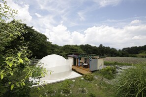 Una casa con una gran estructura abovedada, un cobertizo pequeño y un jardín.