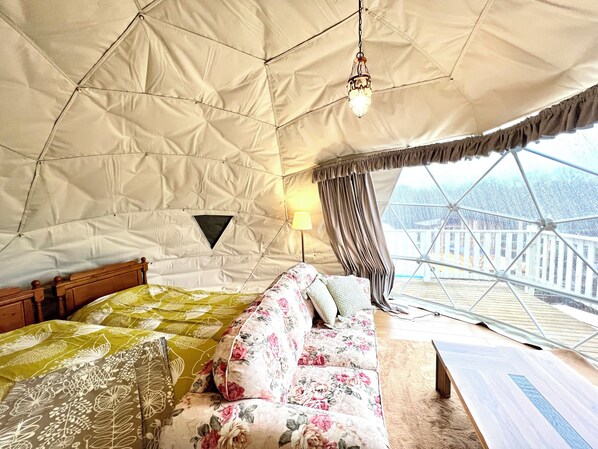 Una habitación con carpa, una cama, un sofá, un lámpara colgante y vistas por una ventana.