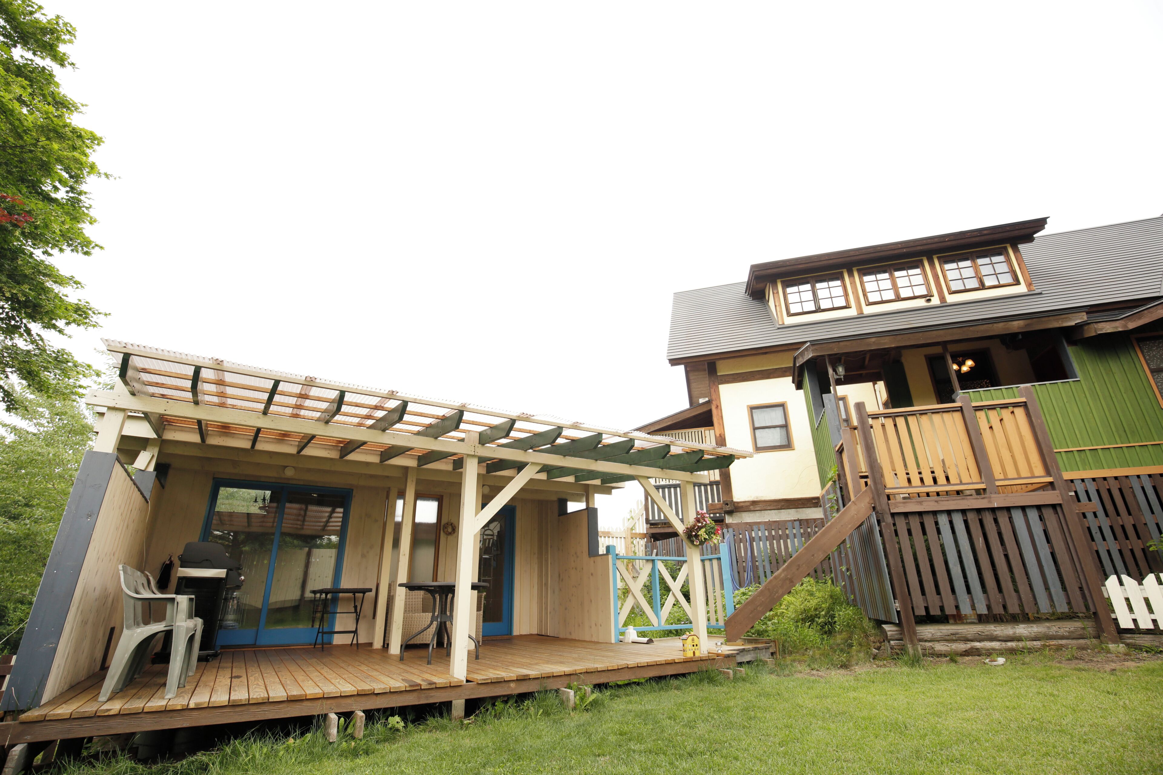 A wooden deck with a pergola, a small table, and a chair.