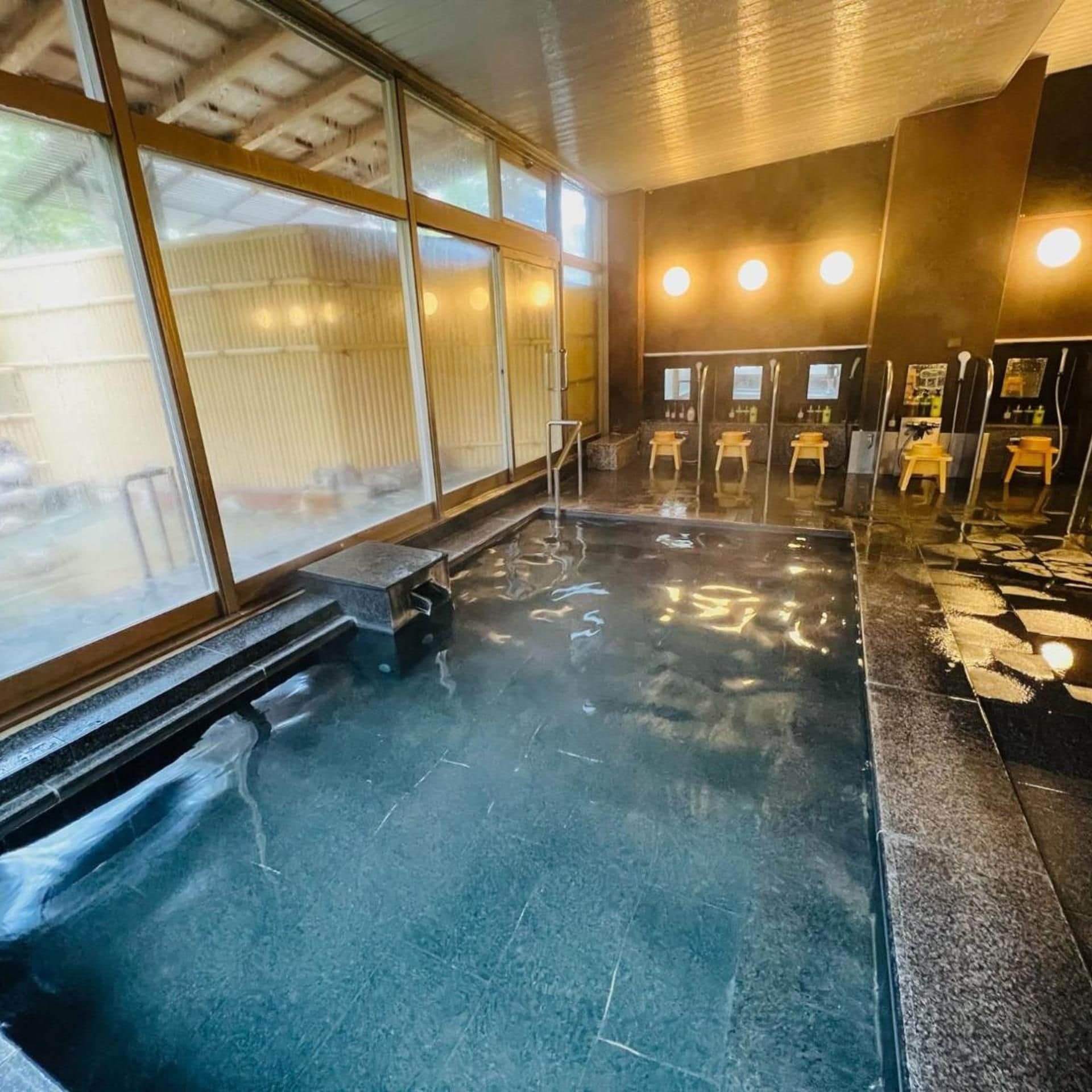 A public sauna with a bench, a tiled floor, and multiple benches with mirrors and shelves.