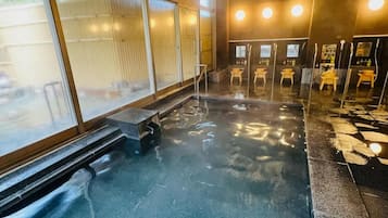 A public sauna with a bench, a tiled floor, and multiple benches with mirrors and shelves.
