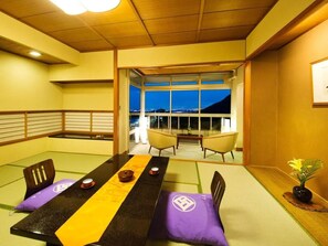 Una habitación con esteras de tatami, una mesa baja, sillas y vistas a través de un ventanal.