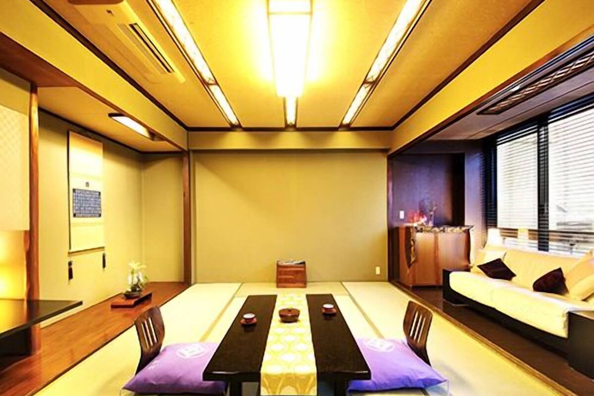 A traditional tatami room with a low table, cushions, and a sofa.