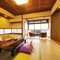 Una habitación con esteras de tatami, una mesita baja, cojines y vistas amplias a través de grandes ventanales.