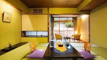 A traditional Japanese room with tatami flooring, a low table with a tea set, and sliding doors leading to an outdoor area.