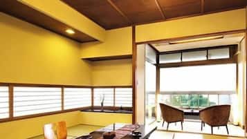 A tatami mat room with a low table, chairs, and a view through a window.