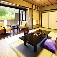 A traditional Japanese room with tatami flooring, a low table, and a sofa.