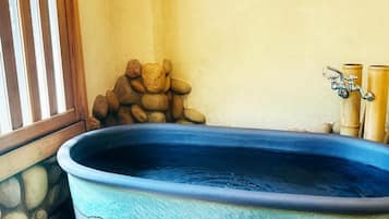 A hot tub with a stone wall and bamboo pillars.