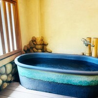 Un jacuzzi con pared de piedra y pilares de bambú.