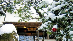 Una escalera cubierta de nieve que conduce a un edificio con una entrada tradicional japonesa.
