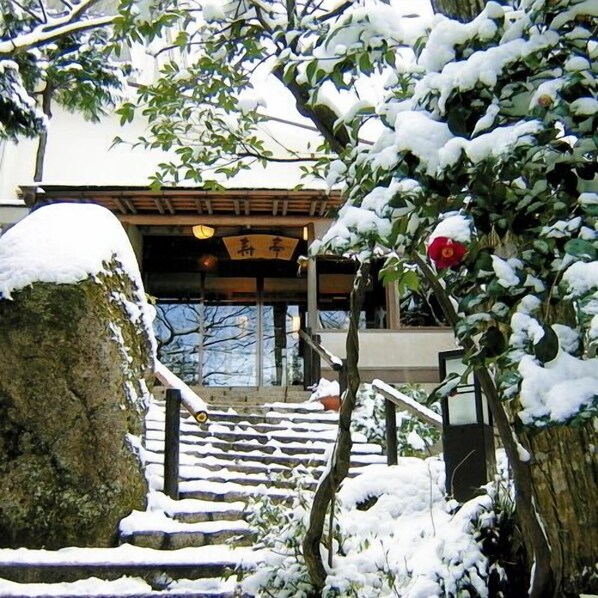 Una escalera cubierta de nieve que conduce a un edificio con una entrada tradicional japonesa.