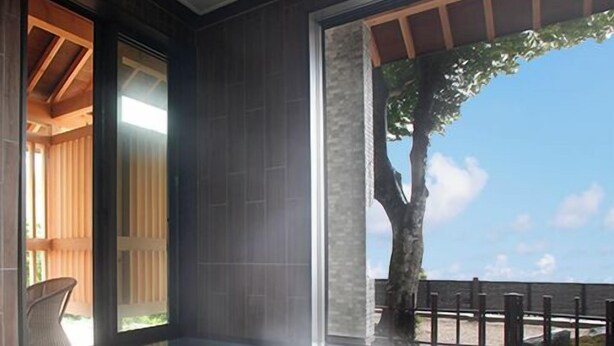 Un área de spa moderna con un banco de madera, una pared de piedra y vistas al cielo.