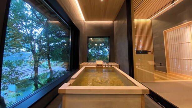 Un interior moderno con un ventanal grande, techo de madera y una fuente de agua rectangular.