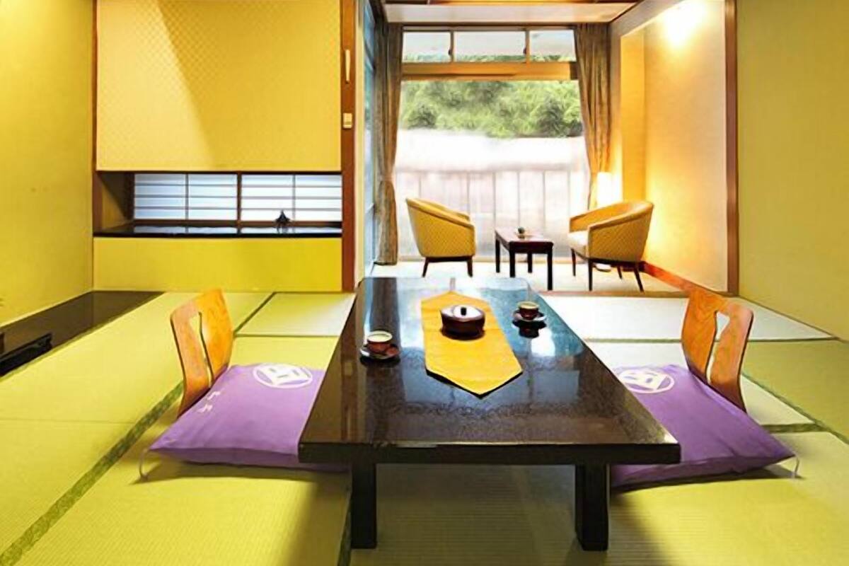 A traditional Japanese-style room with tatami flooring, a low table, and sliding doors leading to an outdoor area.
