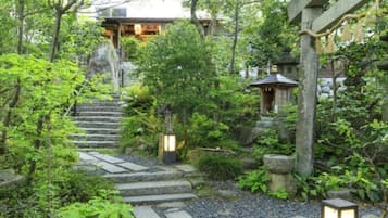 A traditional Japanese garden with stone pathways, lanterns, and a wooden structure.