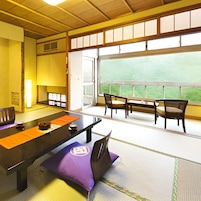 Una habitación de estilo japonés tradicional con suelo de tatami, una mesa baja con cojines y vistas a la vegetación a través de amplias ventanas.