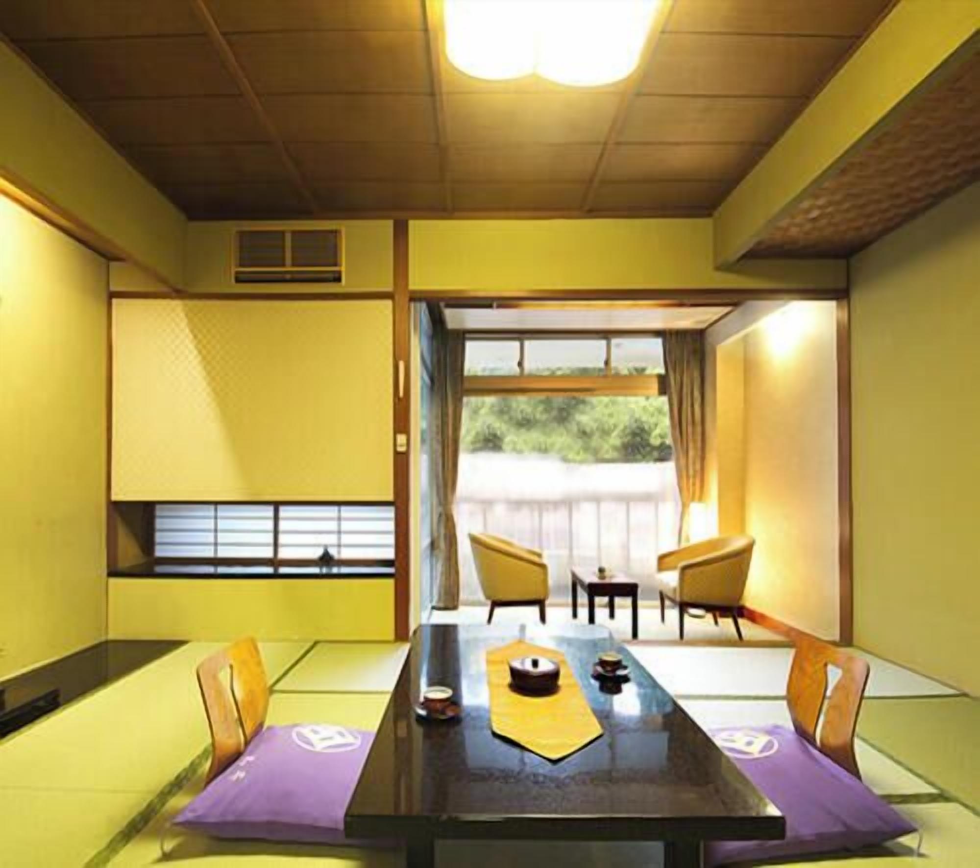 Una habitación japonesa tradicional con suelo de tatami, una mesa baja y puertas correderas que dan a un espacio exterior.