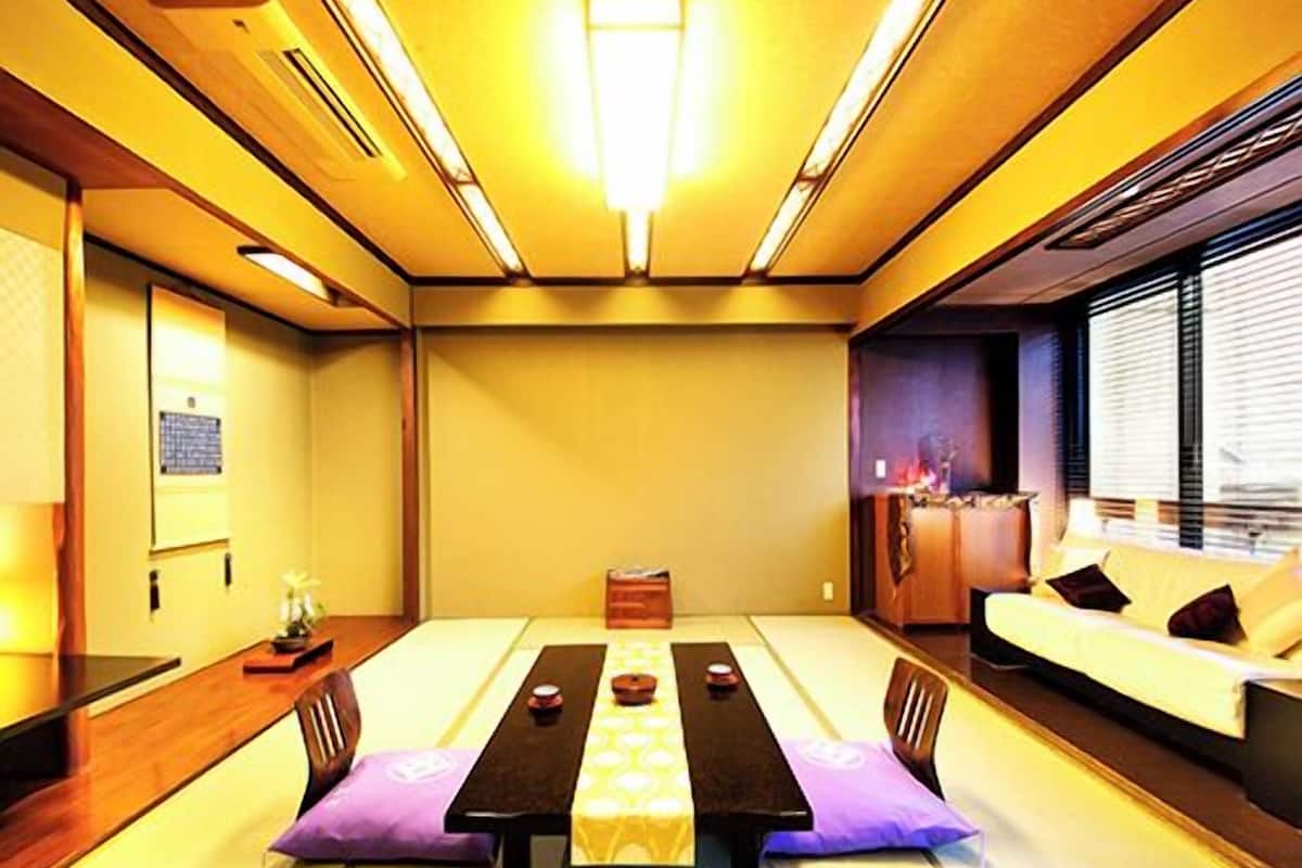 A traditional tatami mat room with a low table, chairs, and a sofa.