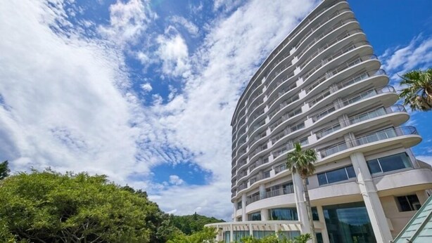 A multi-story hotel with balconies, a curved facade, and a clear sky. - Hotel Harvest Katsuura (Katsuura)