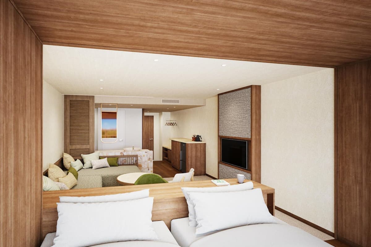 Ein modernes Hotelzimmer mit einem Holzkopfteil, einer Couch, einem Esstisch und einer Küchenzeile.