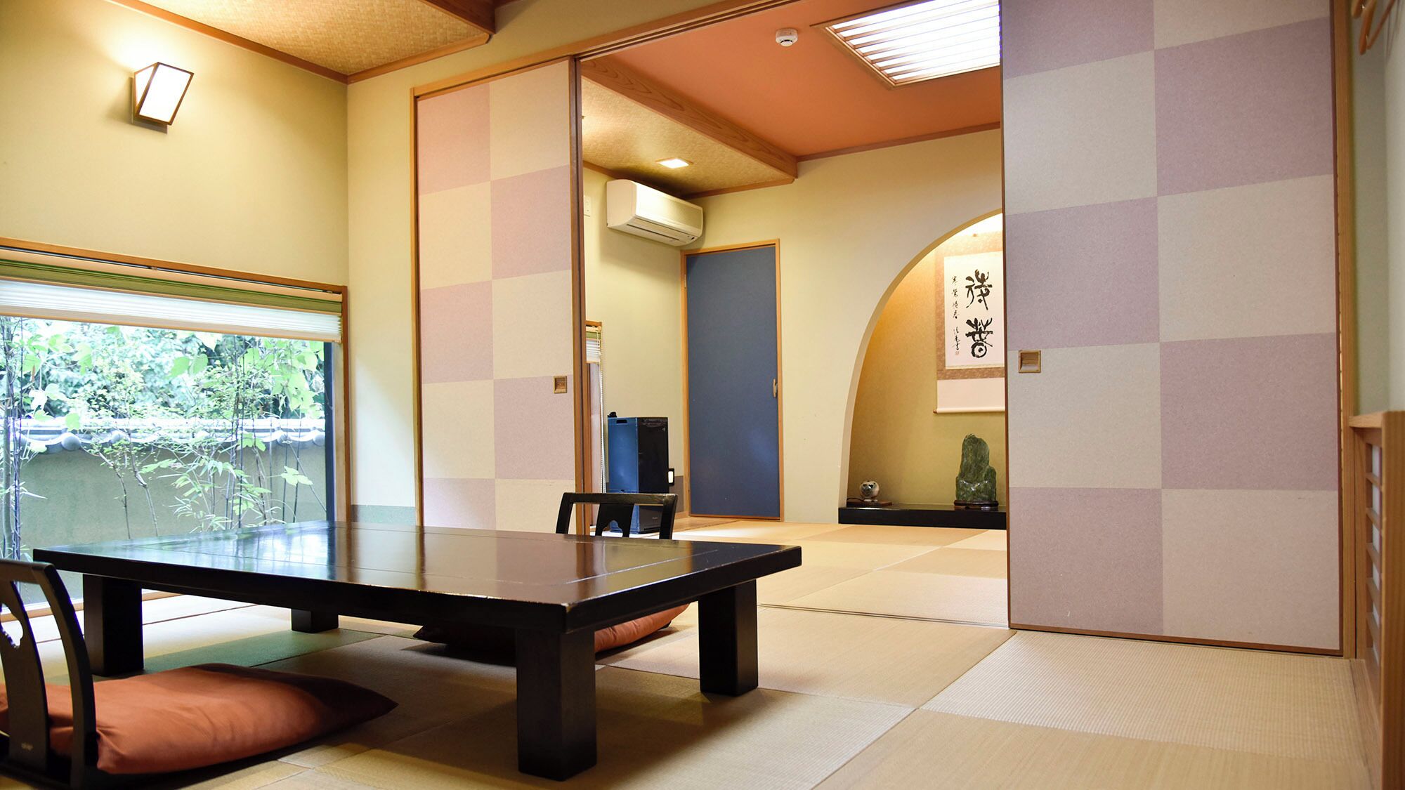 Ein traditioneller japanischer Raum mit Tatami-Boden, einem niedrigen Tisch und einer Schiebetür.