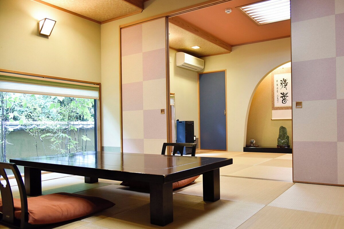 A traditional Japanese room with tatami flooring, a low table, and a sliding door.