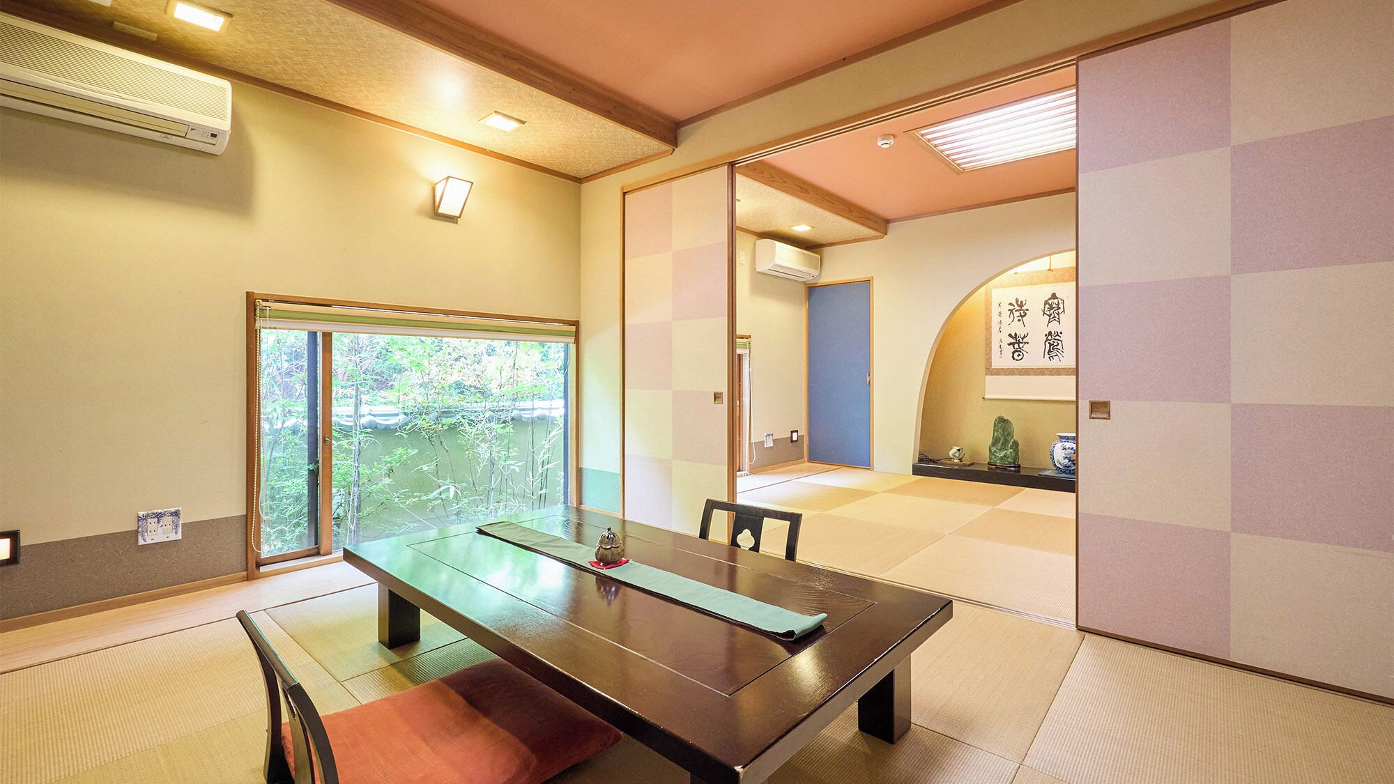 Ein traditioneller japanischer Raum mit Tatami-Böden, einem niedrigen Tisch und verschiebbaren Türen.