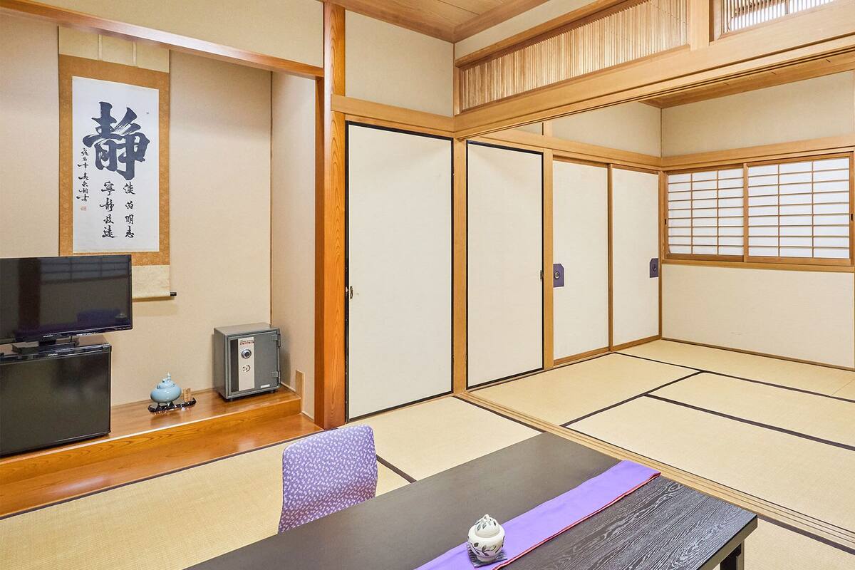 Een traditionele Japanse kamer met tatami vloeren, een televisie, een kluis en een shoji scherm.