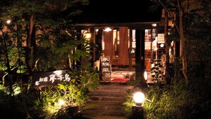 Een traditionele Japanse entree met een houten poort, een pad van stenen en verlichte borden.